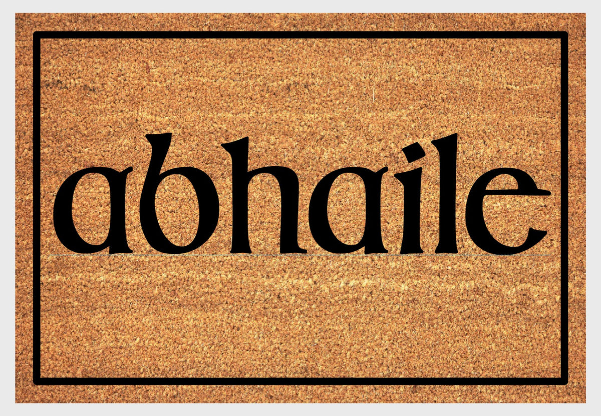Abhaile Irish Gaelic coir doormat with bold black Celtic-style lettering on natural golden coir surface with black border, plain white background