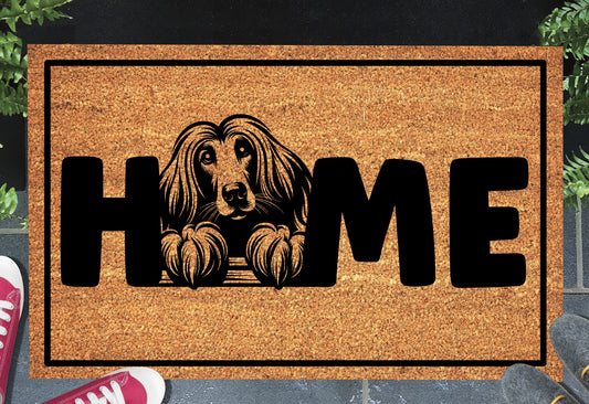 Afghan Hound coir doormat with portrait illustration of an Affie replacing the letter O in bold black HOME lettering, on a natural golden coir surface with black border, styled on a slate doorstep.