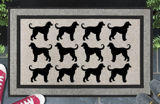 Afghan Hound Parade all-weather doormat in a doorway setting — rows of Afghan Hound silhouettes with flowing coat, long elegant neck, and curled tail in a repeating pattern on a woven polyester mat with black border