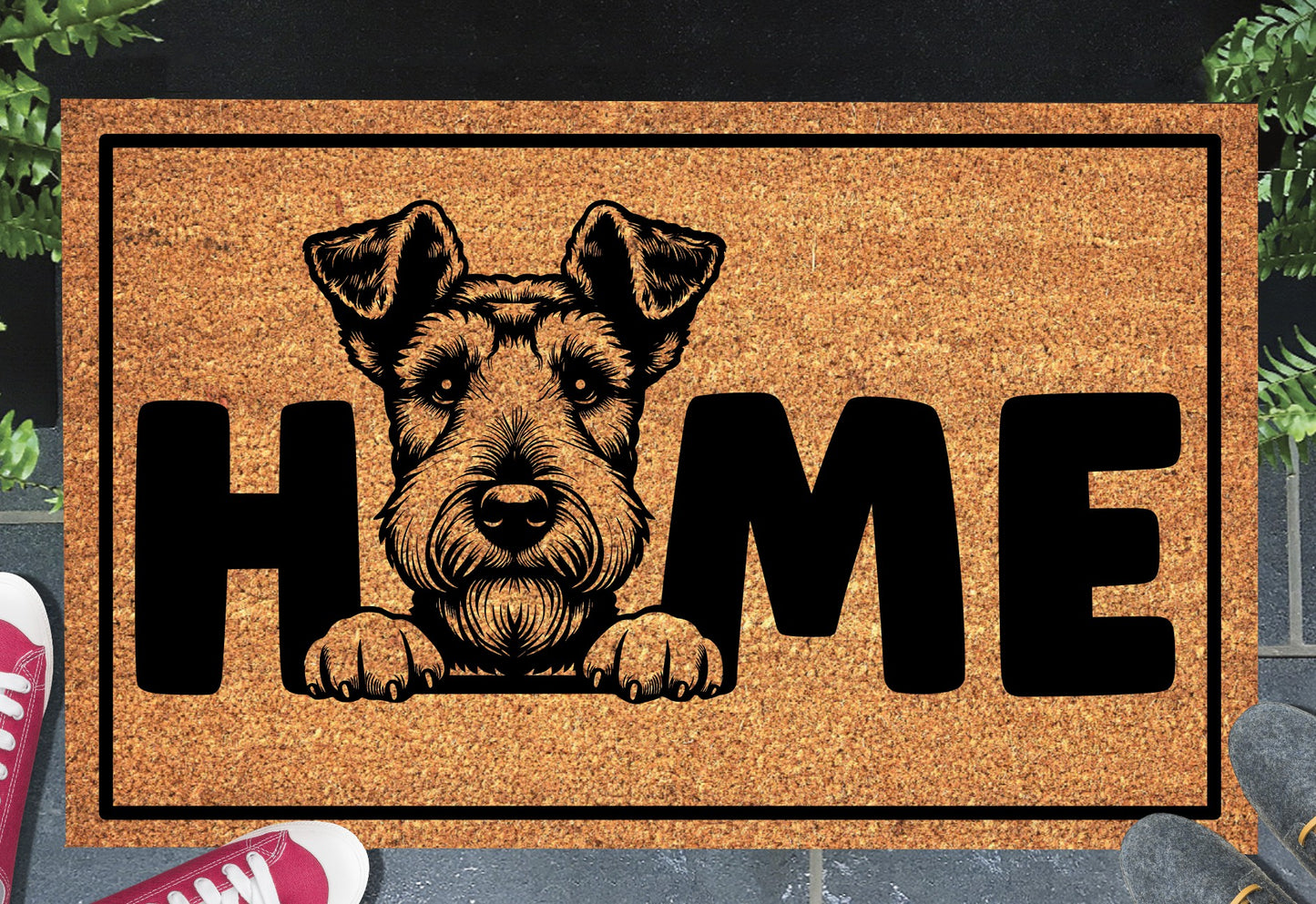 Airedale Terrier King of Terriers coir doormat with bold black HOME lettering and Airedale Terrier illustration replacing the letter O, on a natural golden coir surface with black border, styled on a slate doorstep with red sneakers and green plants