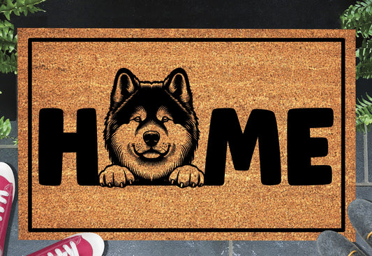 Akita coir doormat with portrait illustration of an Akita replacing the letter O in bold black HOME lettering, on a natural golden coir surface with black border, styled on a slate doorstep.