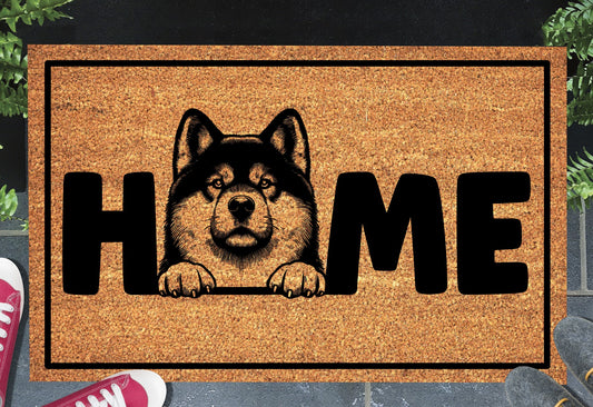 Akita coir doormat with portrait illustration of an Akita replacing the letter O in bold black HOME lettering, on a natural golden coir surface with black border, styled on a slate doorstep.