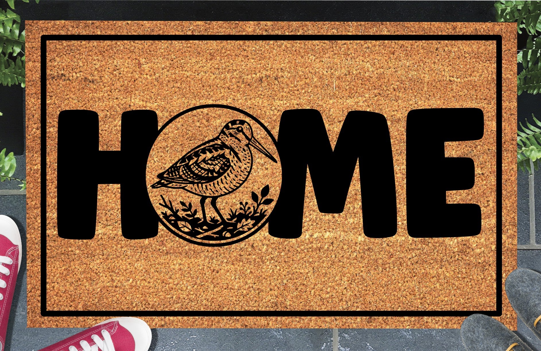 American Woodcock coir doormat in entryway — Bogsucker full-body illustration in circular botanical frame replaces the letter O in HOME on natural coir