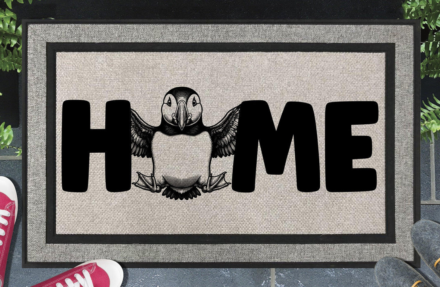 Atlantic Puffin Sea Parrot all-weather doormat in entryway — full-body standing Puffin illustration replaces the letter O in HOME on a woven polyester welcome mat