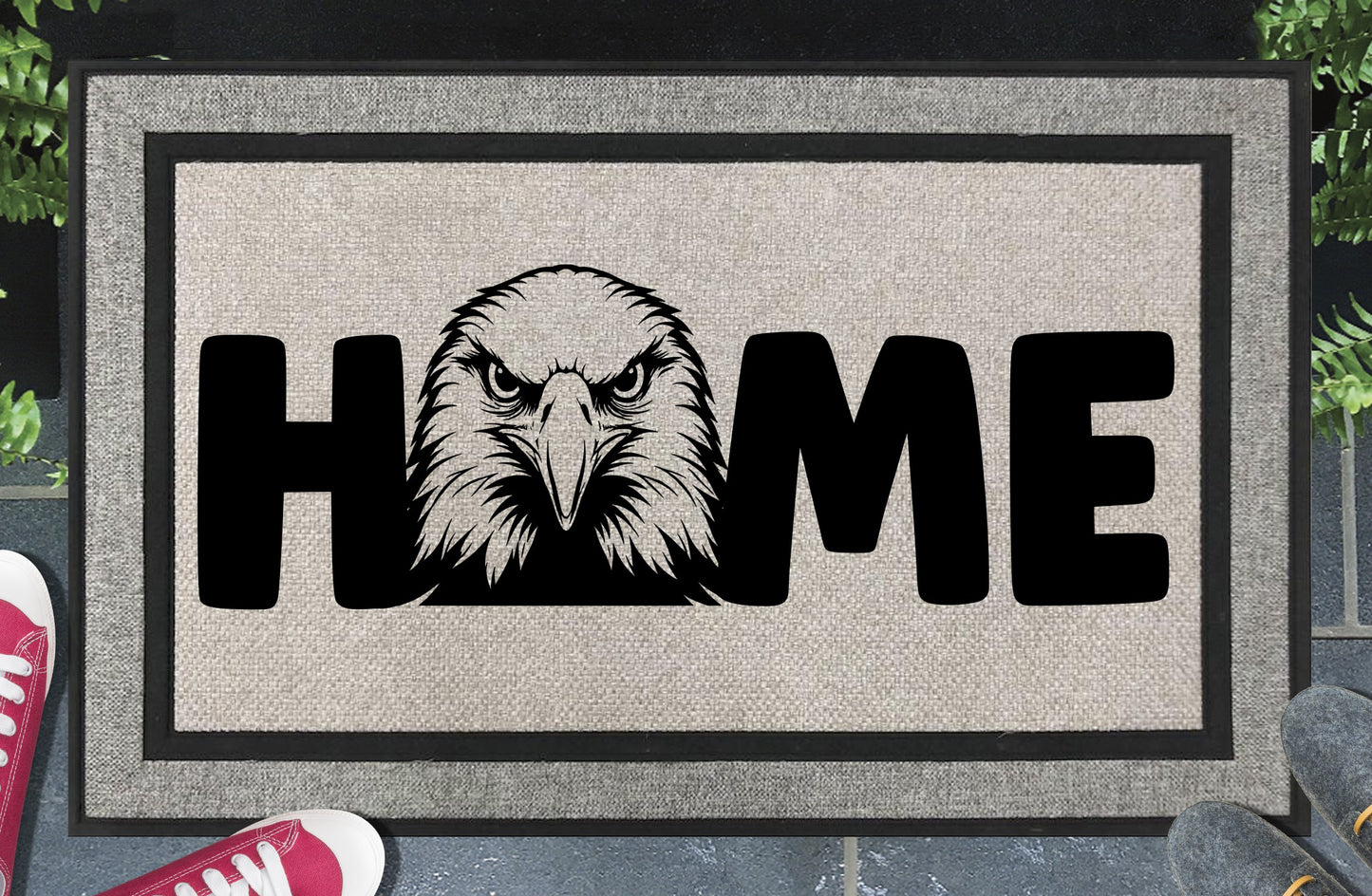 American Bald Eagle HOME all-weather doormat in doorway lifestyle shot — light grey linen-look woven polyester mat, front-facing Bald Eagle head illustration replaces the letter O in HOME, 18x30 size shown