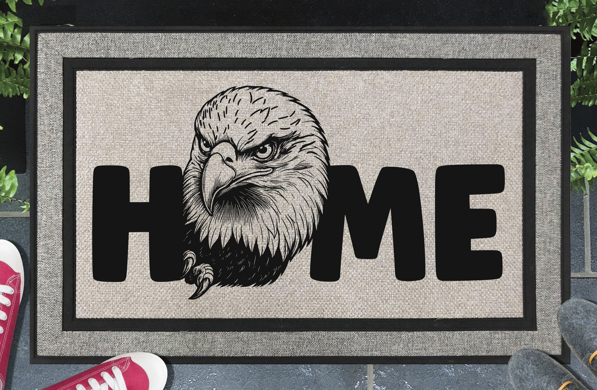 American Bald Eagle HOME all-weather doormat in doorway lifestyle shot — light grey linen-look woven polyester mat, large angled Bald Eagle head and talon illustration replaces the letter O in HOME, 18x30 size shown