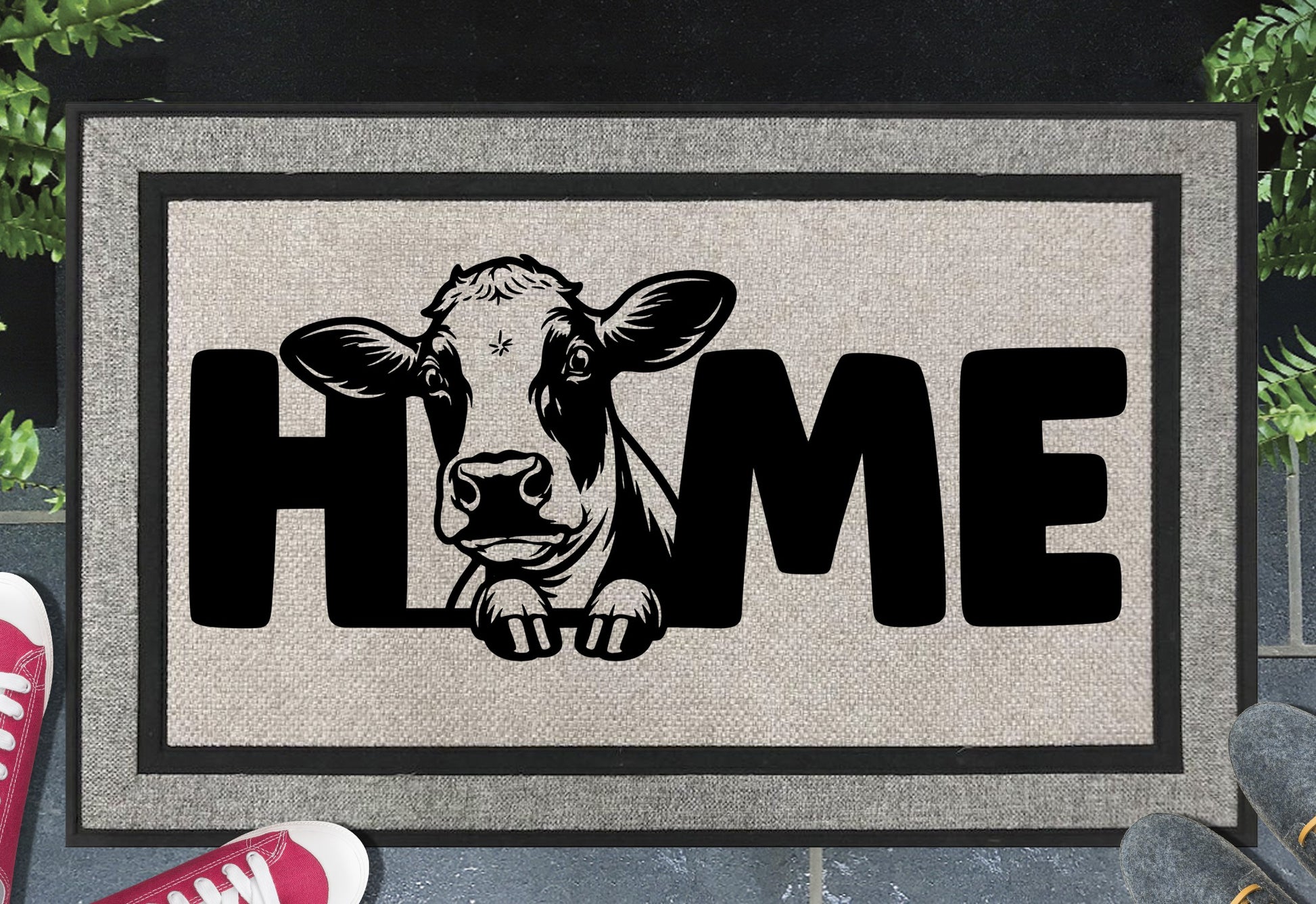 Holstein Cow Doormat #1 all-weather mat with cow peering through HOME lettering on grey woven polyester, placed at front door entryway on dark tile