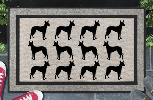 Podenco Parade all-weather doormat in a doorway setting — rows of Podenco silhouettes with large upright ears and lean athletic frame in a repeating pattern on a woven polyester mat with black border