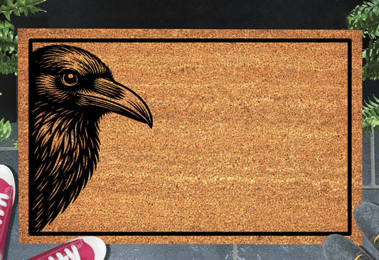 Raven head portrait peeking from the edge of a natural coir doormat on a front porch entryway