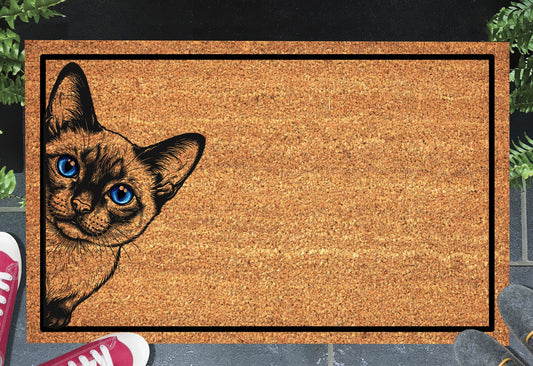 Siamese cat peeking doormat in a doorway setting — natural coir welcome mat