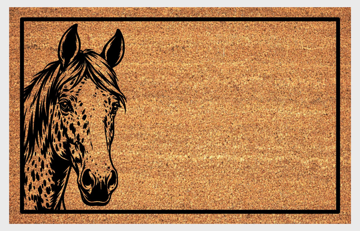 Close-up of an Appaloosa Horse peeking natural coir doormat, showing its spotted face, upright ears, sweeping mane and black rectangular border.