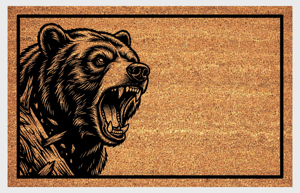 Close-up of a natural coir doormat featuring a Black Bear peeking from the left edge beside a tree trunk, mouth open.