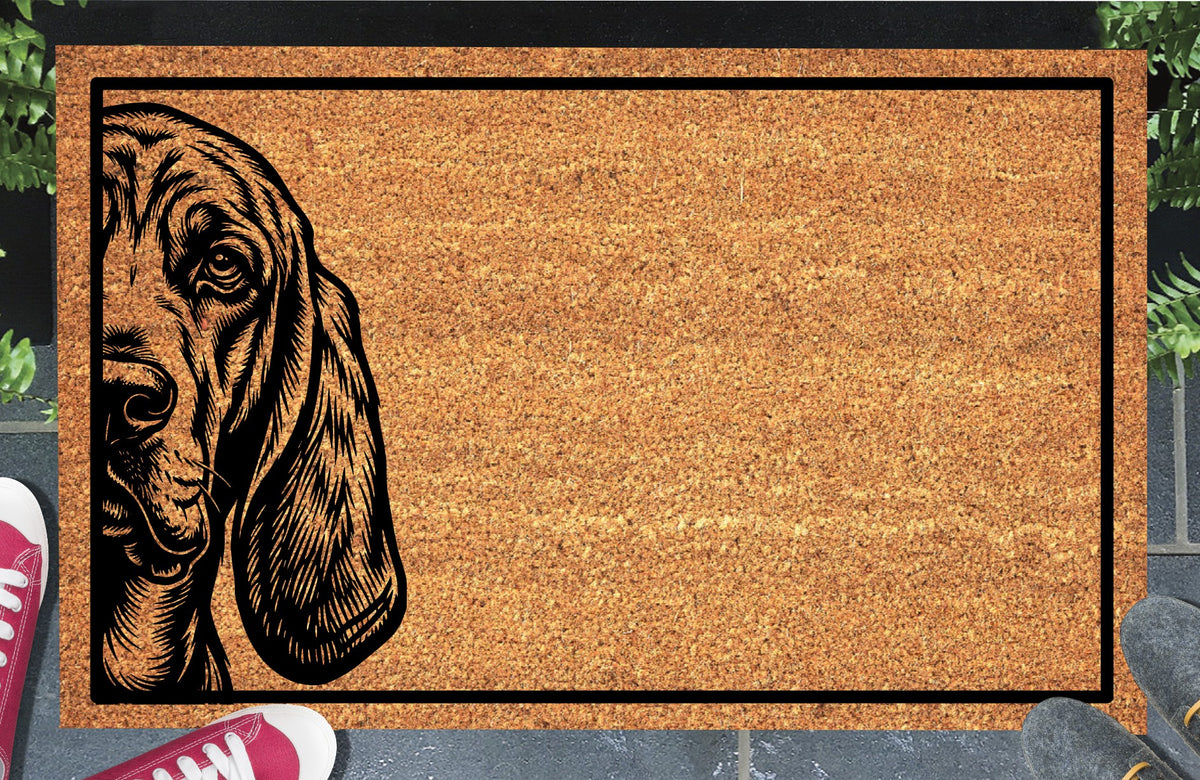 Bloodhound Peeking Doormat #2 with a St. Hubert Hound half-face illustration, long drooping ear and black border, shown in a doorway