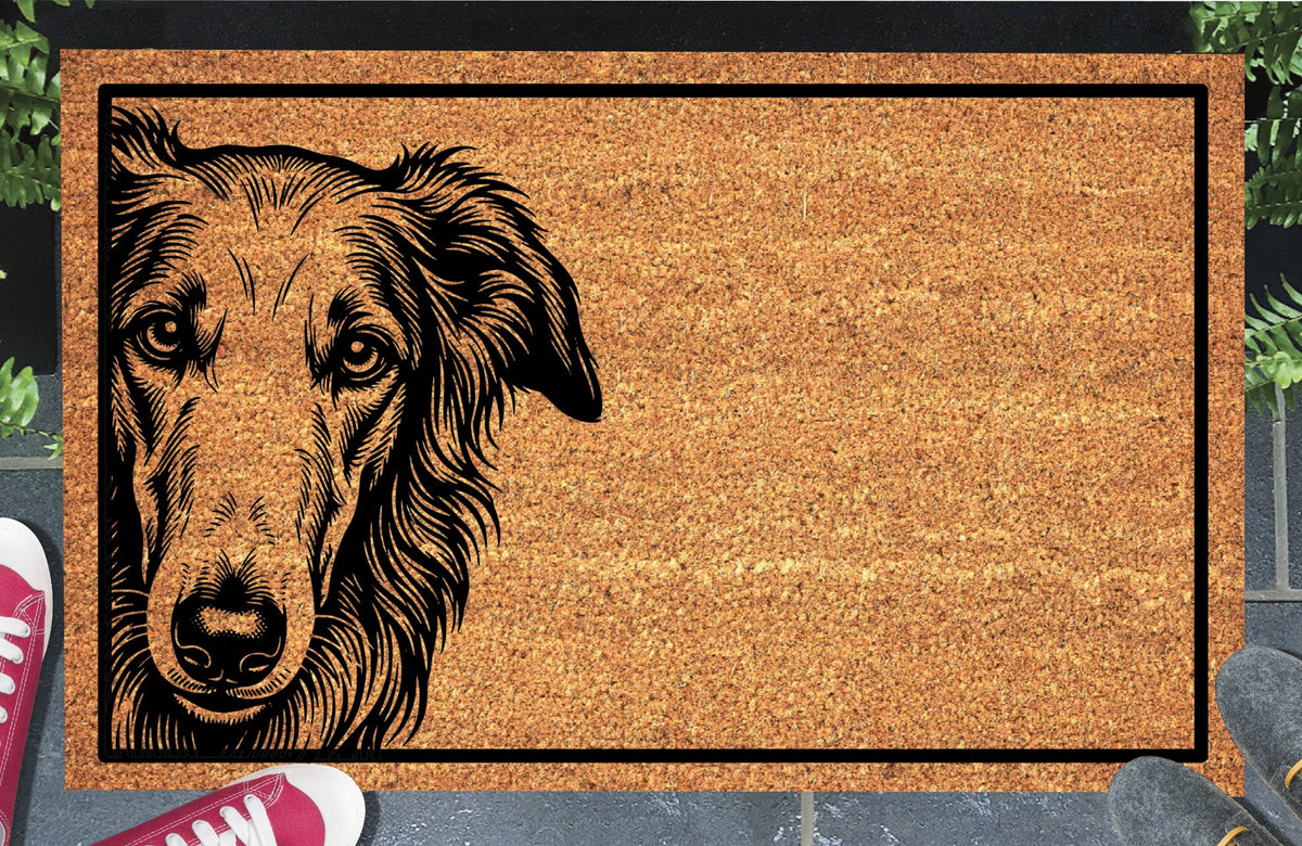 Borzoi Peeking Doormat #2, natural coir welcome mat with a long-muzzled Borzoi portrait peeking from the left edge inside a black rectangular border, shown at a doorway.