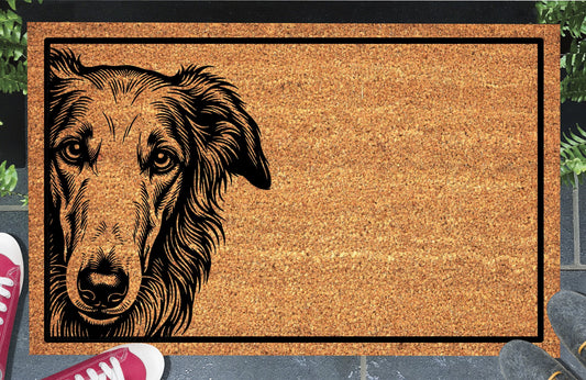 Borzoi Peeking Doormat #2, natural coir welcome mat with a long-muzzled Borzoi portrait peeking from the left edge inside a black rectangular border, shown at a doorway.