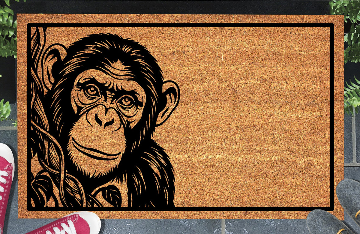 Chimpanzee Peeking coir doormat #1 with a chimp portrait beside a leafy vine and black rectangular border, shown on a doorstep