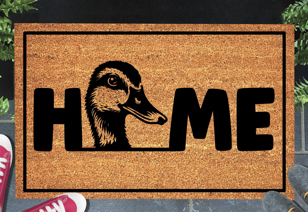 Duck Doormat #1 Mallard Welcome Mat coir doormat — duck head illustration replacing the letter O in HOME, natural coir fiber, non-slip rubber backing, flat lay on dark background