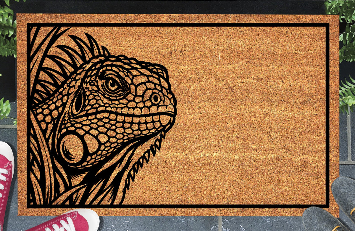 Iguana peeking coir doormat with a detailed Iguana peeking through foliage on the left inside a black rectangular border, styled at an entryway.