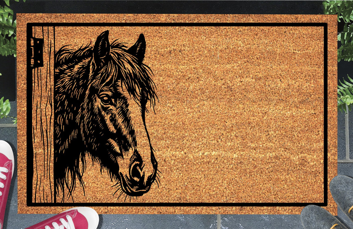 Irish Cob Horse peeking beside a wooden stable door on a natural coir doormat, with a tousled mane, broad facial blaze and black border, shown at an entryway.