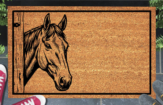 Irish Sport Horse peeking beside a wooden stable door on a natural coir doormat, with upright ears, a swept forelock and black border, shown at an entryway.