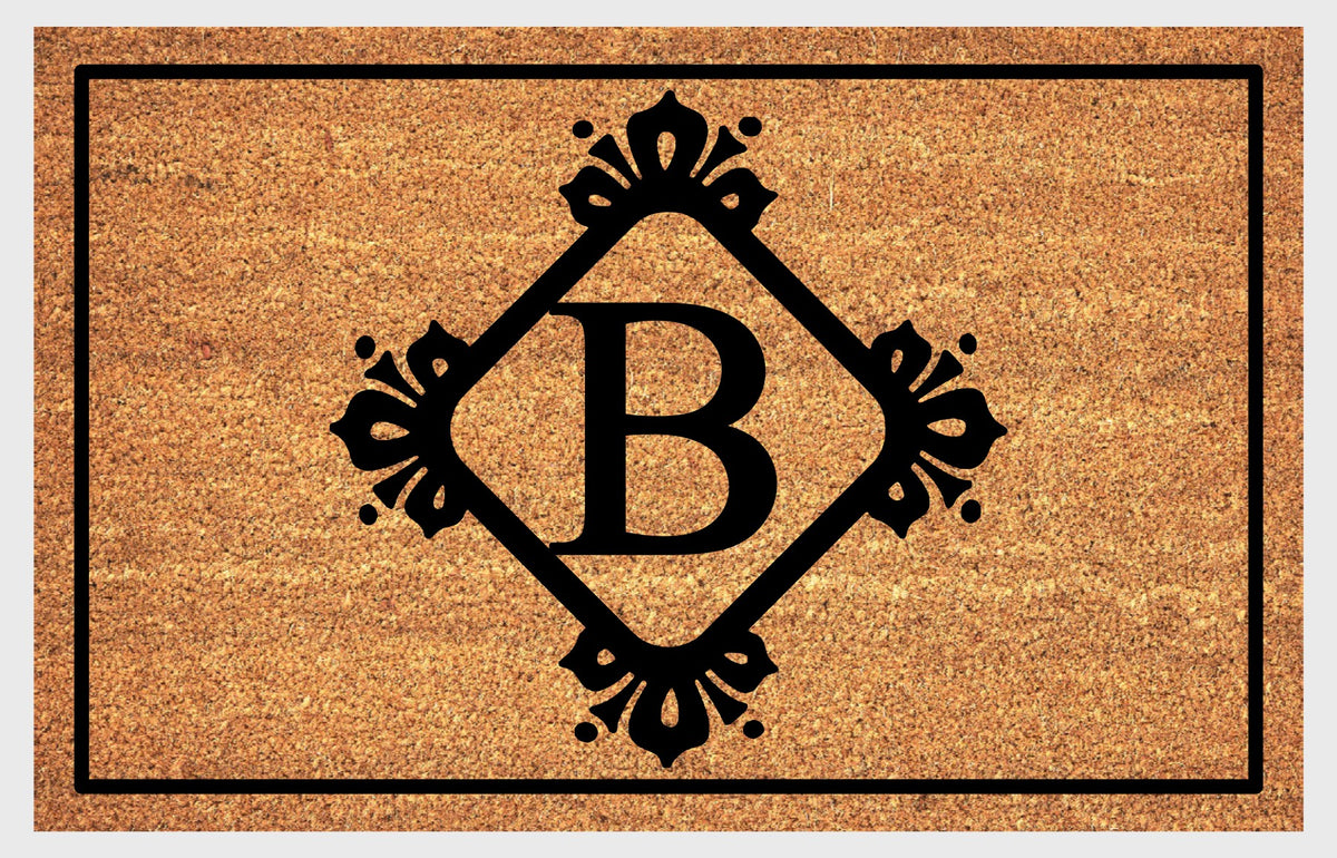 Monogram Letter B doormat in natural coir with an ornate serif letter B in a diamond frame with fleur-de-lis style flourishes and dot accents, with a black border, shown flat.