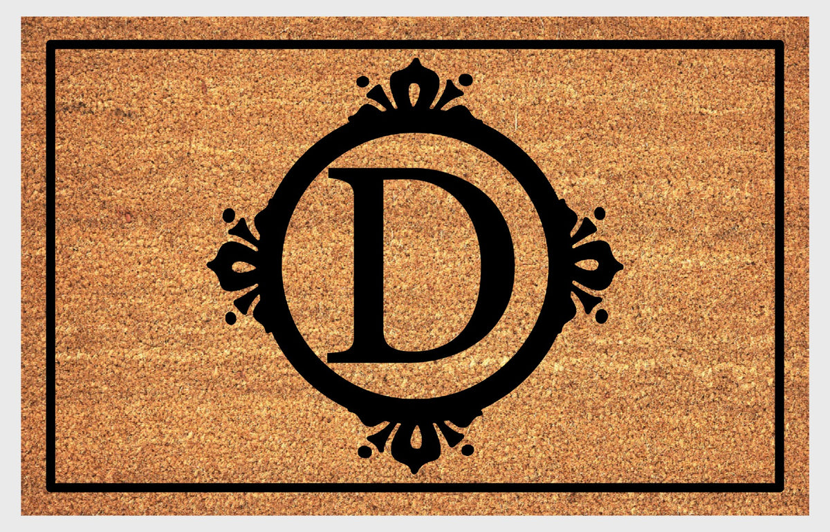 Monogram Letter D doormat in natural coir, featuring a serif D in a circular frame with fleur-de-lis style flourishes, dot accents and a black rectangular border, shown flat.
