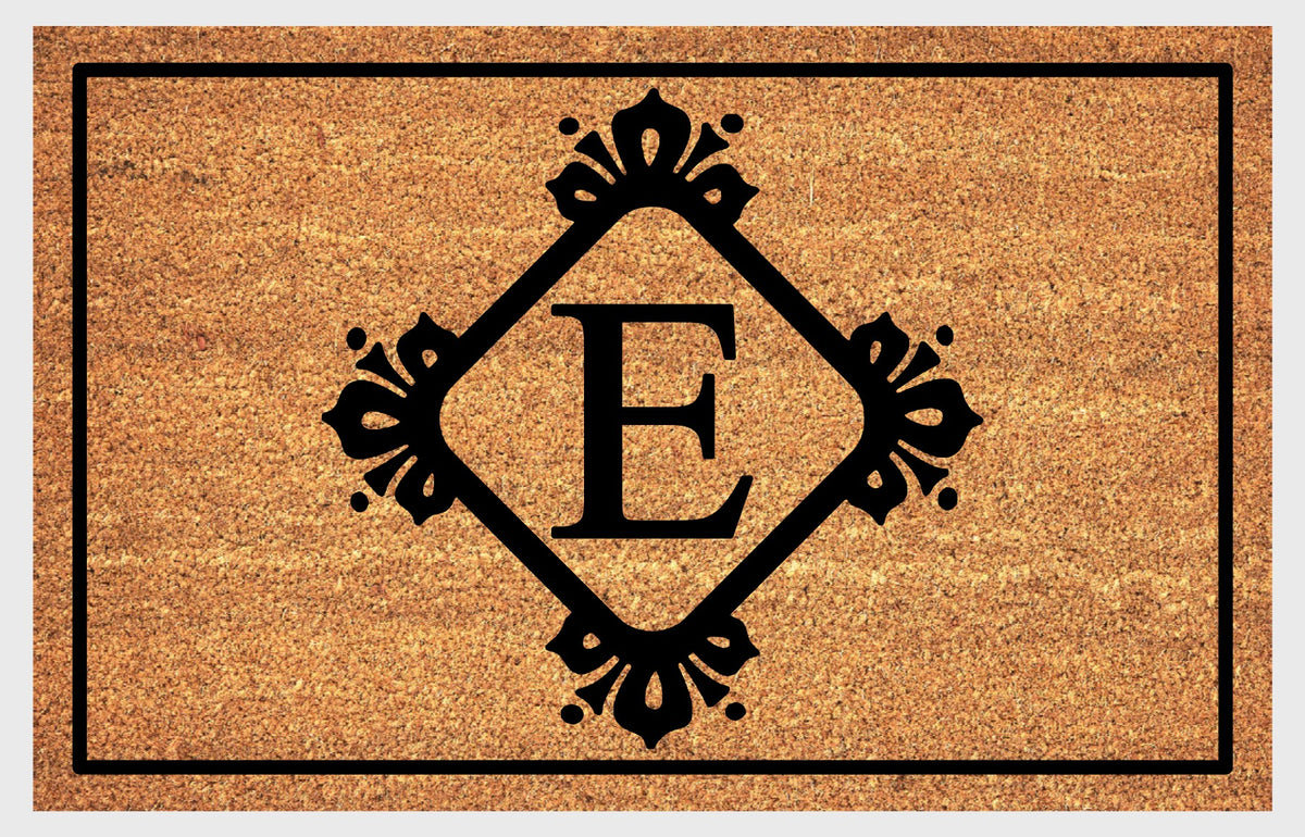 Monogram Letter E doormat in natural coir, showing the ornate serif letter E in a diamond frame with fleur-de-lis style flourishes and dot accents, with a black border, shown flat.