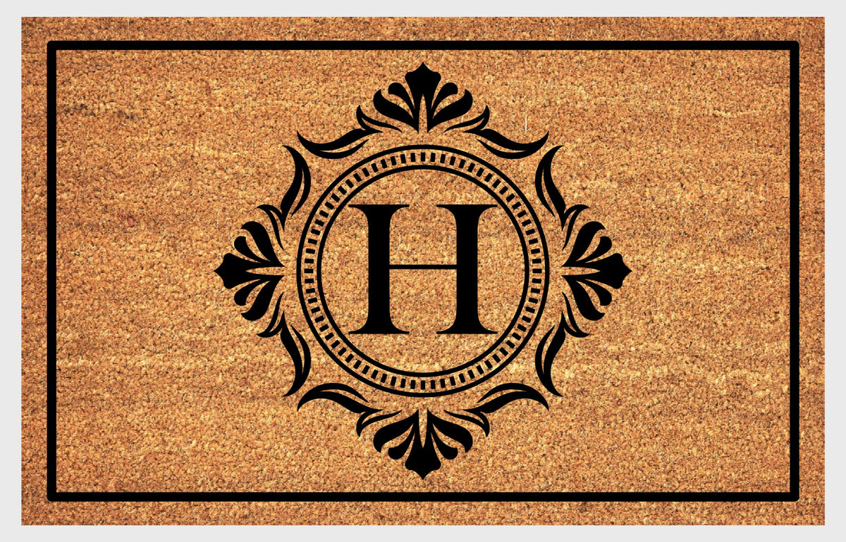 Monogram Letter H doormat in natural coir with an ornate serif letter H in a dotted circular frame, fleur-de-lis style flourishes, and a black border, shown flat.