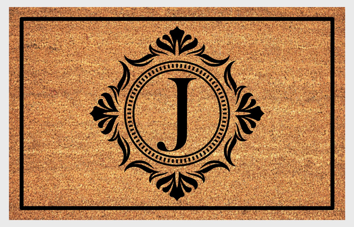 Monogram Letter J doormat in natural coir with an ornate serif letter J in a dotted circular frame, fleur-de-lis style flourishes, and a black border, shown flat.