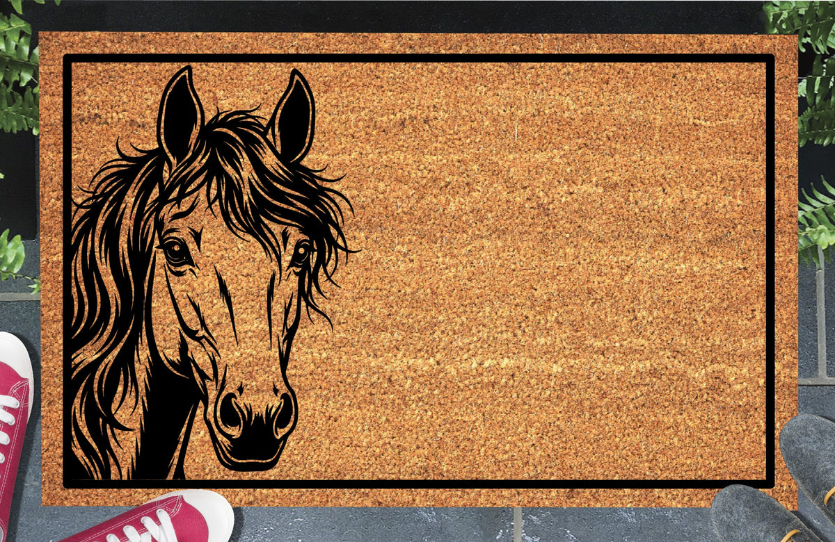 Mustang Horse peeking doormat in natural coir, featuring a black horse portrait peeking from the left edge with upright ears, expressive eyes and a flowing mane inside a black rectangular border, displayed on a doorstep.
