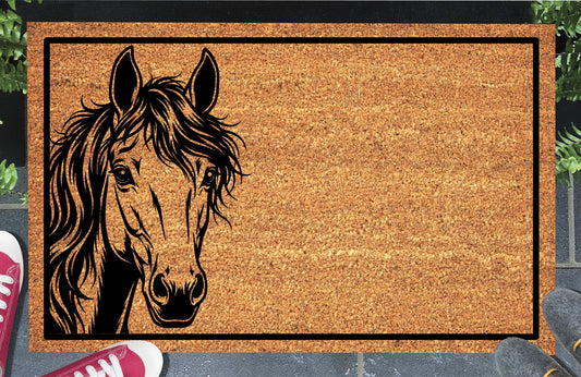 Mustang Horse peeking doormat in natural coir, featuring a black horse portrait peeking from the left edge with upright ears, expressive eyes and a flowing mane inside a black rectangular border, displayed on a doorstep.