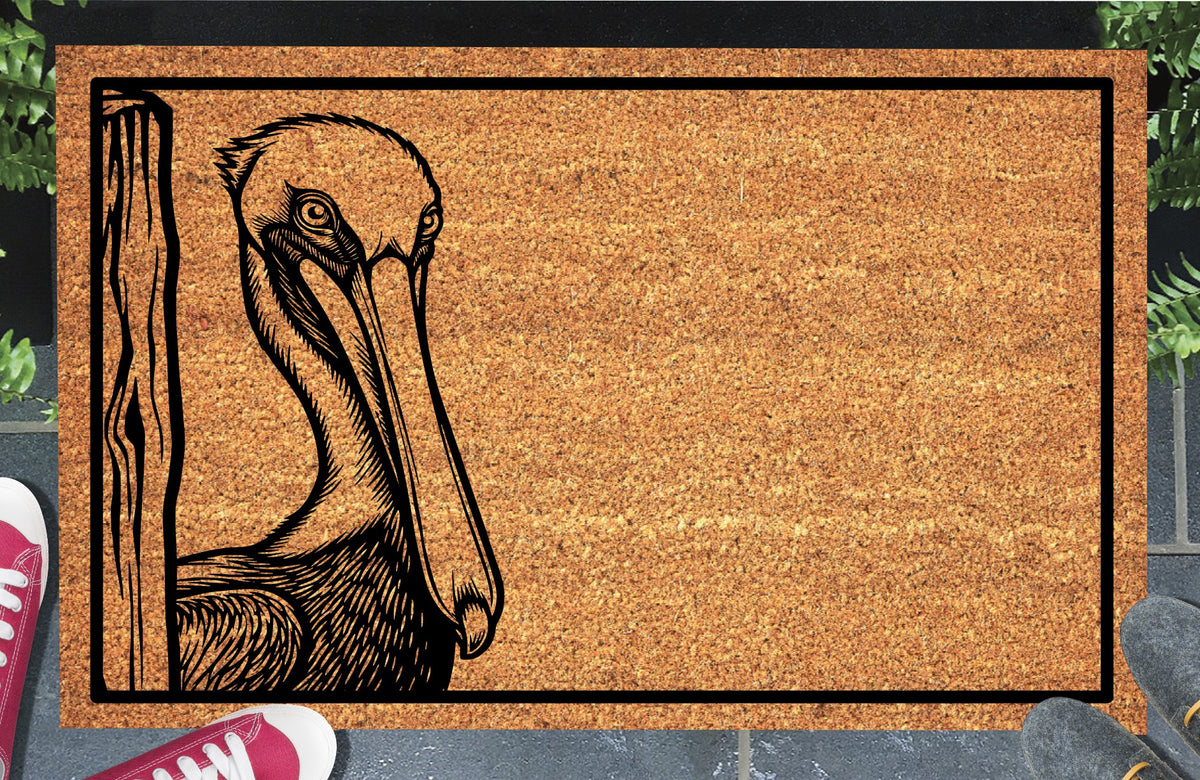 Pelican peeking beside a wood-grain post on a natural coir doormat with a black border, shown at an entryway.