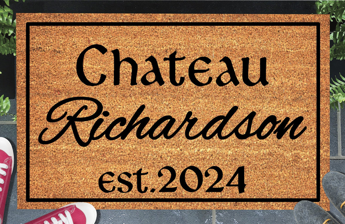 Personalized French Chateau doormat with family name in script, est. 2024 and a black border, displayed on a paved doorstep.