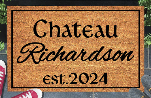 Personalized French Chateau doormat with family name in script, est. 2024 and a black border, displayed on a paved doorstep.