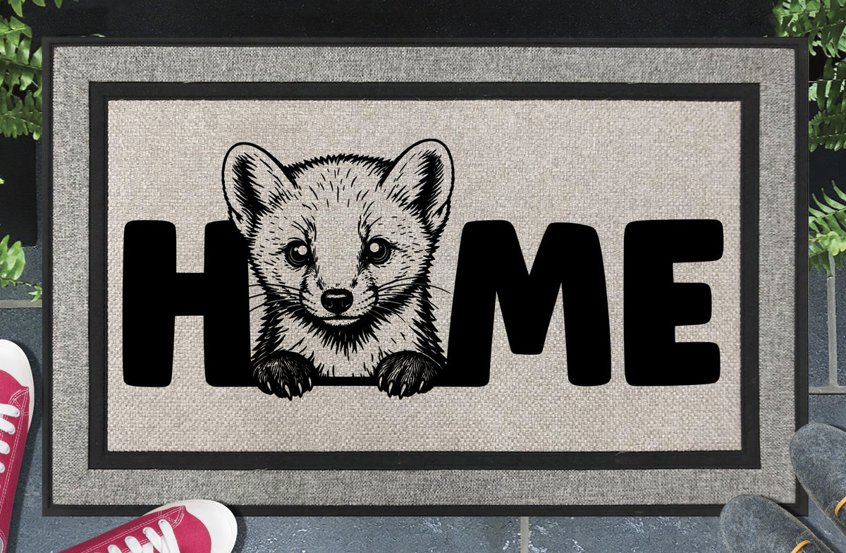 Pine Marten all-weather doormat lifestyle shot — Pine Marten illustration replaces the letter O in HOME, woven polyester mat on a doorstep