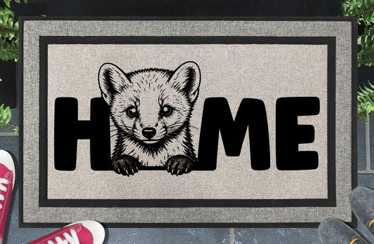 Pine Marten all-weather doormat lifestyle shot — Pine Marten illustration replaces the letter O in HOME, woven polyester mat on a doorstep