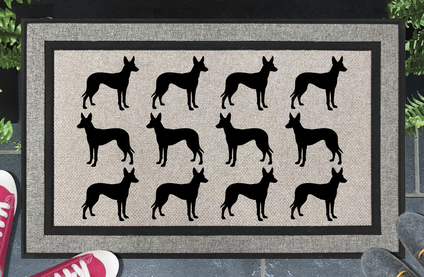 Podenco Parade all-weather doormat in a doorway setting — rows of Podenco silhouettes with large upright ears and lean athletic frame in a repeating pattern on a woven polyester mat with black border
