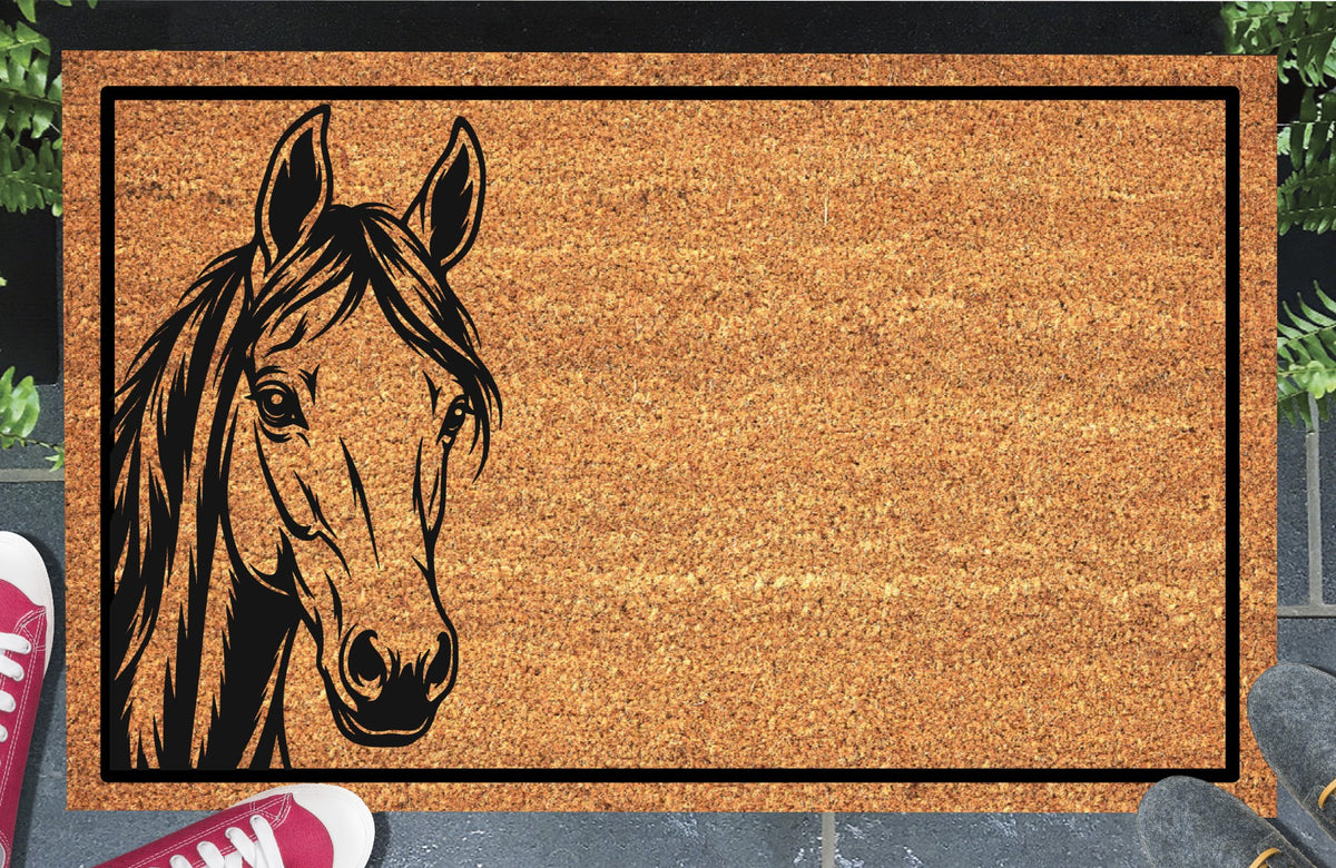 Tennessee Walking Horse peeking from the left edge of a natural coir doormat, with upright ears, a long flowing mane and black rectangular border, shown at a doorstep.