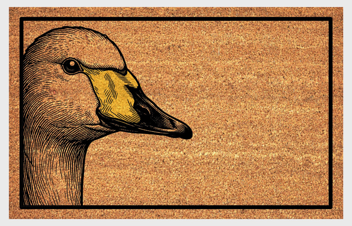 Natural coir doormat featuring a Whooper Swan portrait peeking from the left edge, with finely lined feathers, a yellow-and-black bill and black rectangular border.