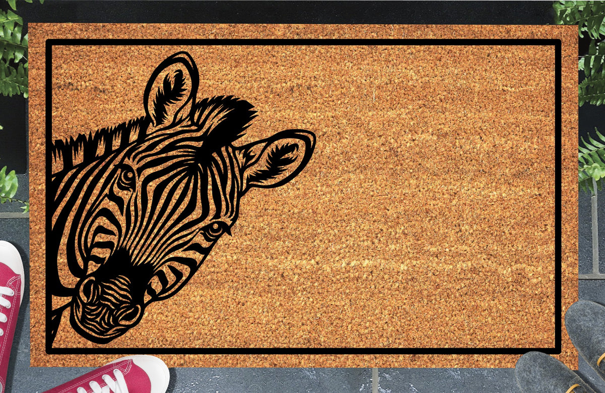 Zebra Peeking Doormat #1, Zebra with a tilted head peeking from the left inside a black border, natural coir mat styled at an entryway.